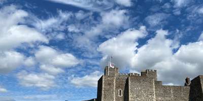 The fortress walls of Dover Castle with a blue sky and fluffy clouds