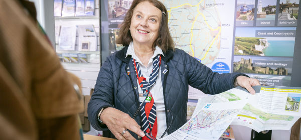 A female member of the visitor information team showing a map and guide to a visitor.
