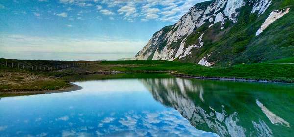 Chalk cliffs, blue sky and clouds reflected in a pool of water